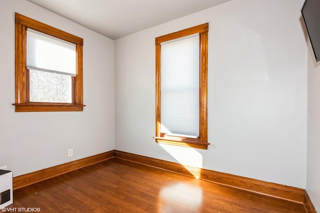 spare room featuring dark wood-style floors and baseboards