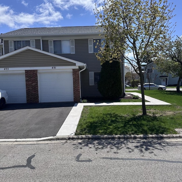 view of front of property featuring driveway, a front yard, brick siding, and a garage