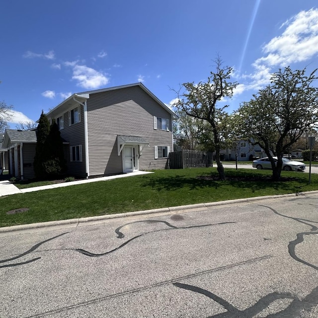 view of side of home featuring fence and a lawn