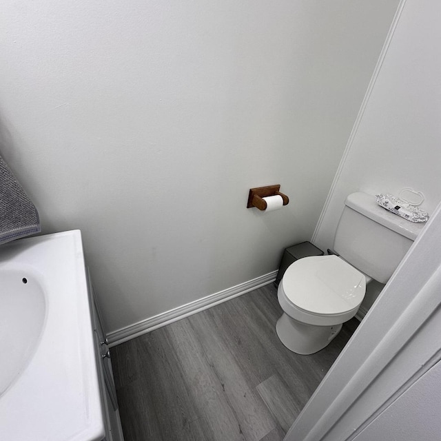 bathroom with baseboards, wood finished floors, toilet, and vanity