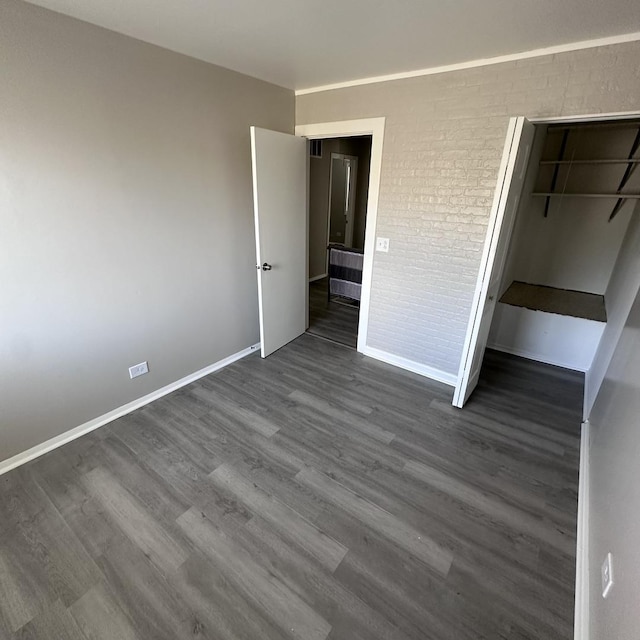 unfurnished bedroom featuring dark wood-style flooring, a closet, and baseboards