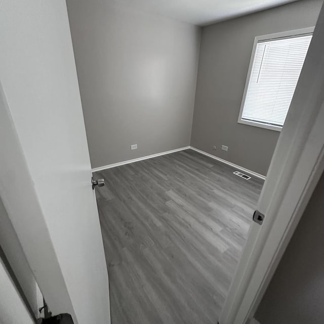 unfurnished room featuring baseboards, visible vents, and wood finished floors