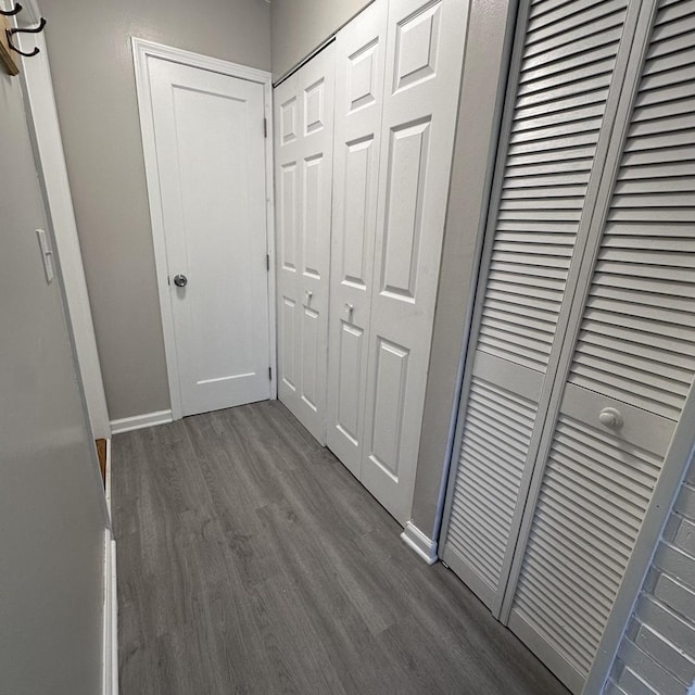 corridor with dark wood-style flooring and baseboards