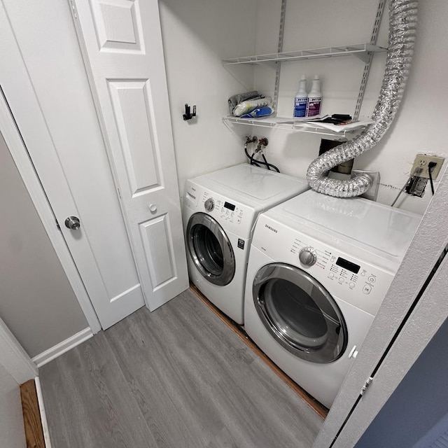 washroom with wood finished floors, separate washer and dryer, and laundry area