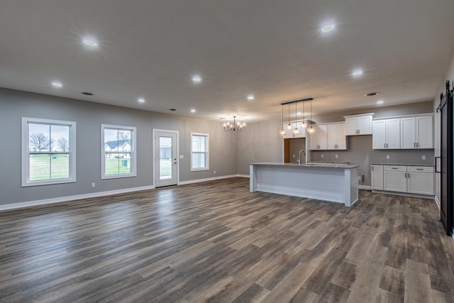 kitchen featuring a center island with sink, white cabinets, dark wood-style floors, open floor plan, and a sink