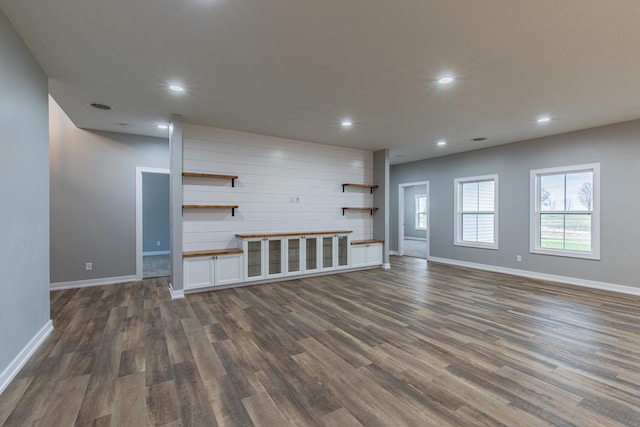 unfurnished living room with baseboards, dark wood-type flooring, visible vents, and recessed lighting