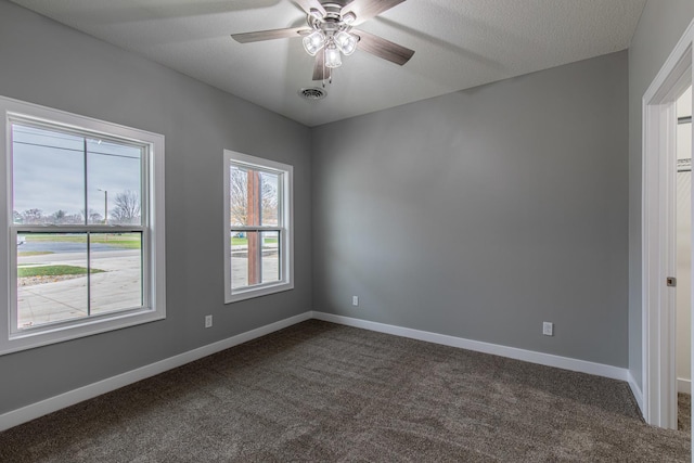 unfurnished room featuring visible vents, dark carpet, a ceiling fan, a textured ceiling, and baseboards