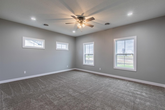 unfurnished room with visible vents, dark carpet, a textured ceiling, and baseboards