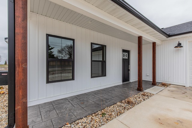 entrance to property with covered porch and roof with shingles