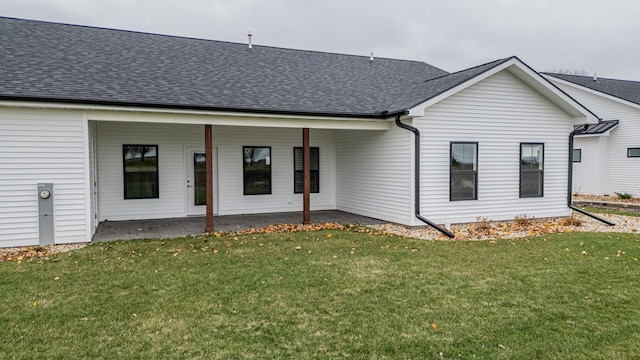 back of house featuring a yard, a shingled roof, and a patio