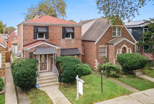 view of front of home with brick siding, a chimney, and roof with shingles