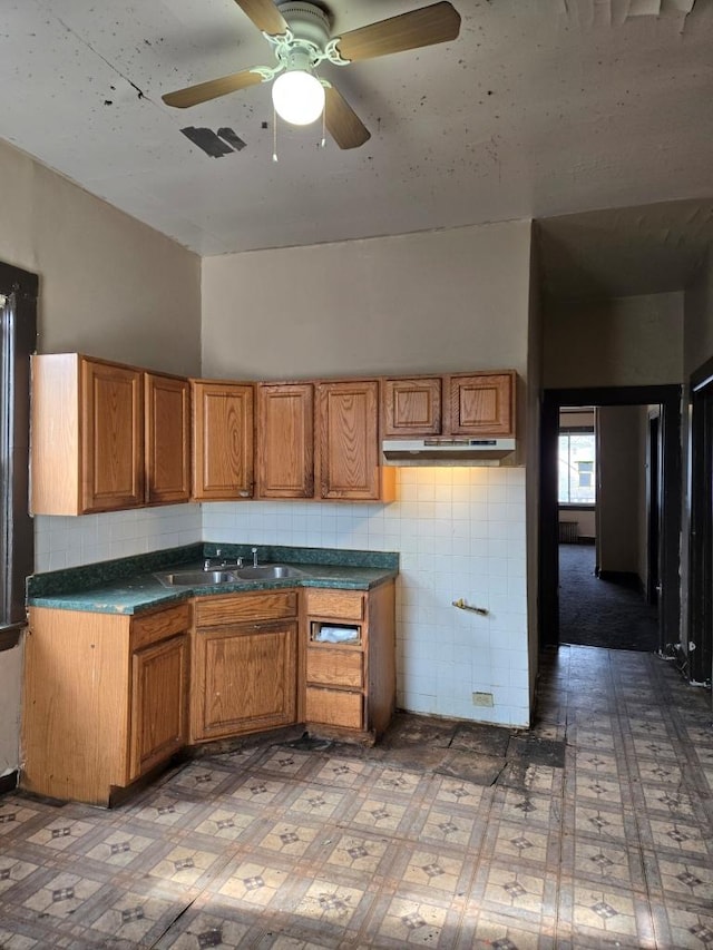 kitchen featuring dark countertops, brown cabinetry, a sink, and tile patterned floors