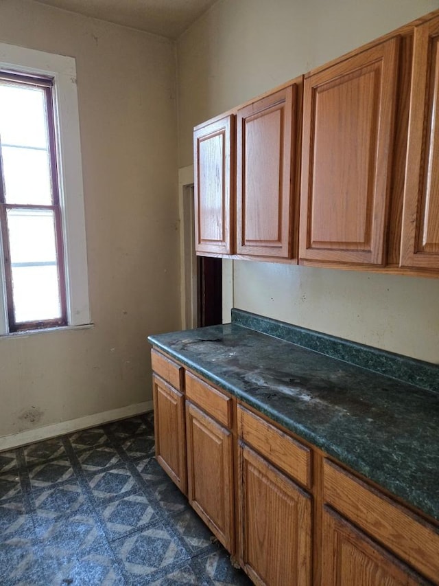 kitchen featuring brown cabinets, dark floors, a healthy amount of sunlight, and baseboards