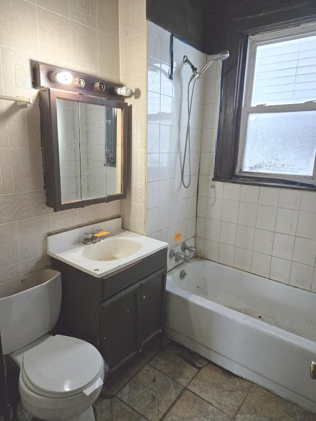 full bathroom featuring washtub / shower combination, toilet, vanity, and tile walls