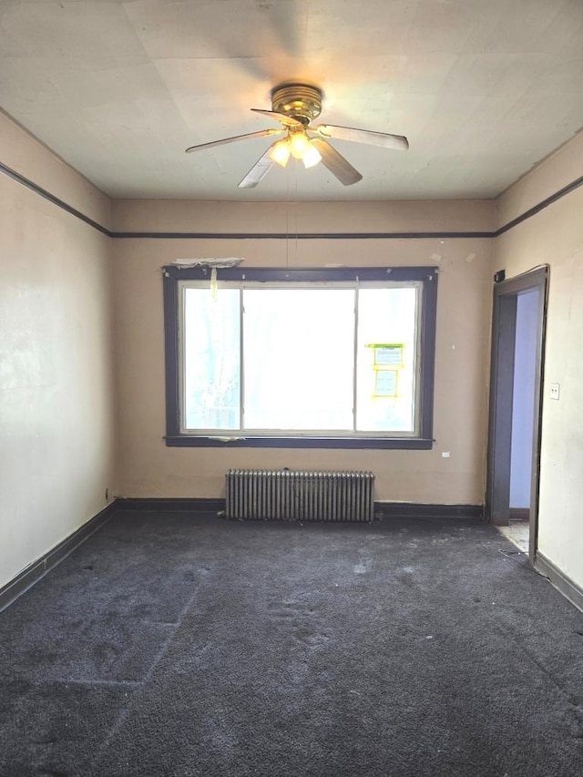 spare room featuring radiator heating unit, dark carpet, and baseboards