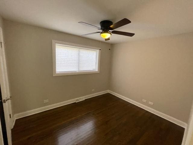 spare room with dark wood-style floors, baseboards, and a ceiling fan