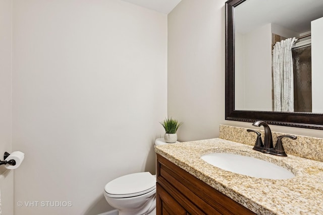 bathroom featuring toilet, a shower with shower curtain, and vanity