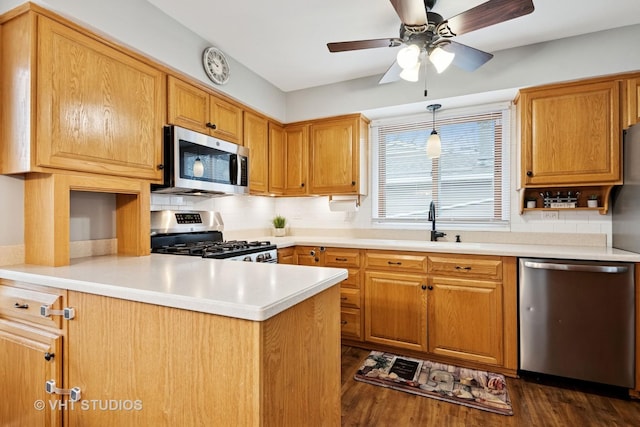 kitchen with stainless steel appliances, dark wood-style flooring, a peninsula, and backsplash