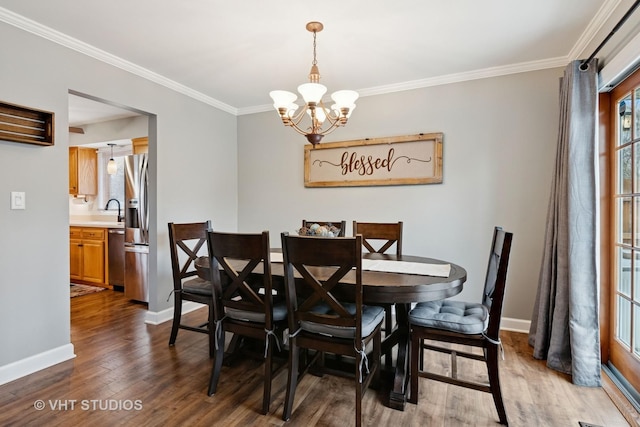 dining area with crown molding, a notable chandelier, wood finished floors, and baseboards