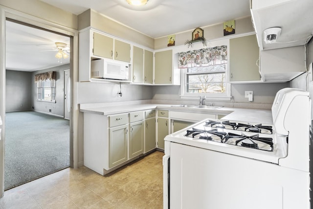 kitchen featuring light colored carpet, light countertops, a ceiling fan, a sink, and white appliances