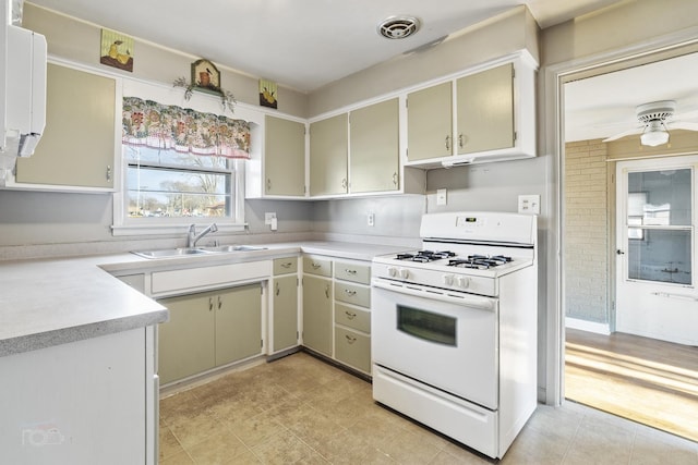 kitchen with white range with gas cooktop, visible vents, ceiling fan, light countertops, and a sink