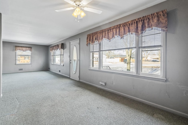 carpeted empty room featuring a ceiling fan, visible vents, and baseboards