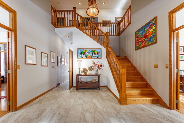 staircase with recessed lighting, baseboards, and a high ceiling