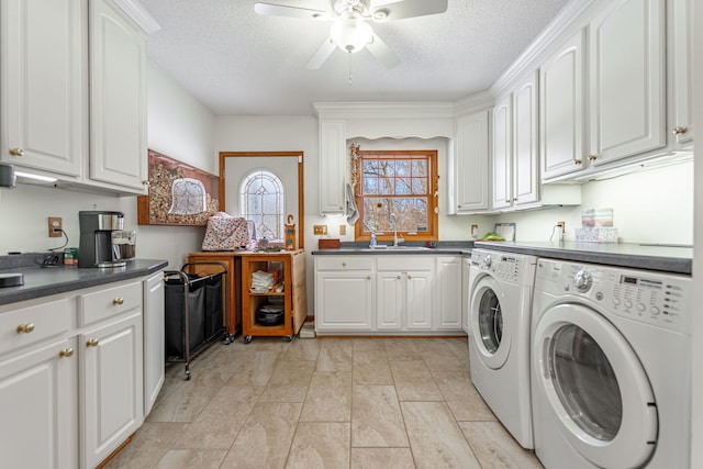 laundry area featuring cabinet space, washing machine and dryer, a sink, a textured ceiling, and ceiling fan