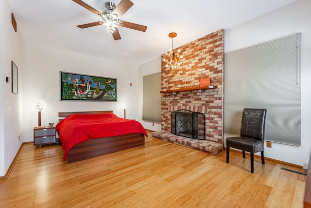 bedroom featuring a brick fireplace, baseboards, and wood finished floors