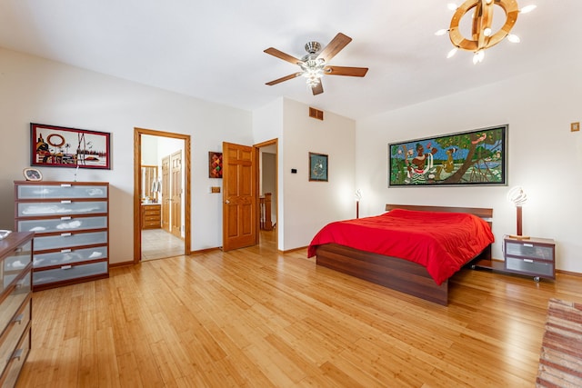 bedroom with a ceiling fan, ensuite bath, baseboards, and wood finished floors