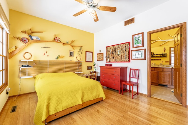 bedroom with light wood-type flooring, multiple windows, visible vents, and connected bathroom