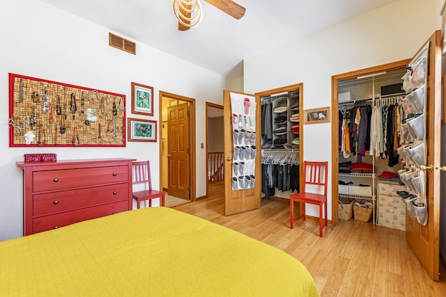 bedroom featuring a ceiling fan, visible vents, wood finished floors, and two closets