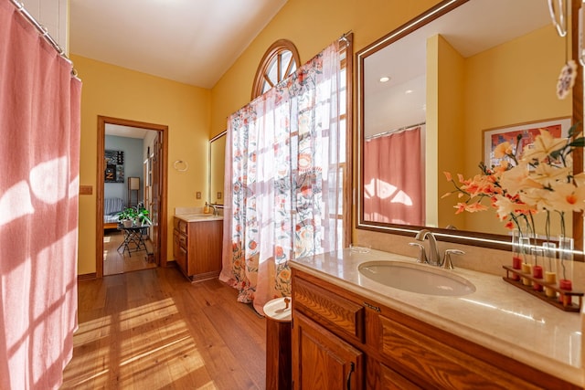 full bath featuring hardwood / wood-style flooring, vaulted ceiling, and vanity