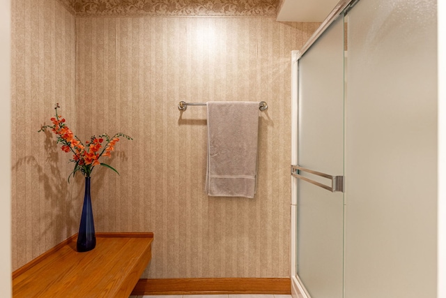 bathroom featuring wallpapered walls and a shower with door