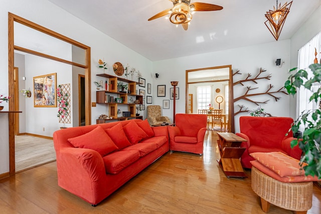 living area featuring light wood-style floors, baseboards, and a ceiling fan