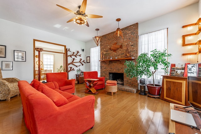 living area featuring a brick fireplace, wood finished floors, and a ceiling fan