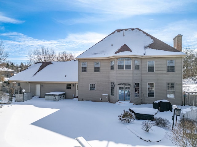 snow covered property with a garage, a jacuzzi, fence, and entry steps