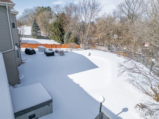 snowy yard featuring a fenced backyard and a jacuzzi