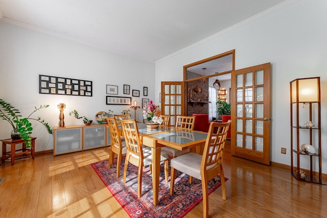 dining area featuring wood-type flooring, ornamental molding, baseboards, and french doors