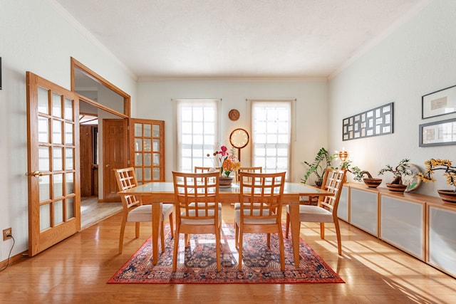 dining area with ornamental molding, wood finished floors, and french doors