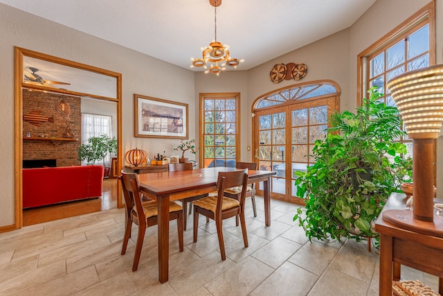 dining space featuring a brick fireplace and a chandelier