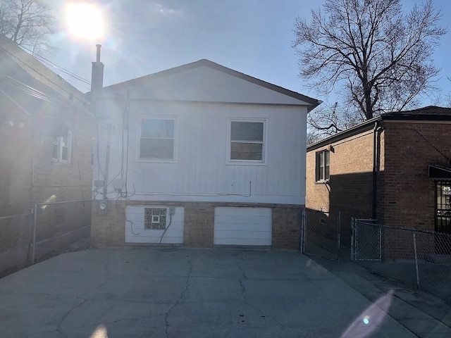 rear view of house featuring a garage and fence