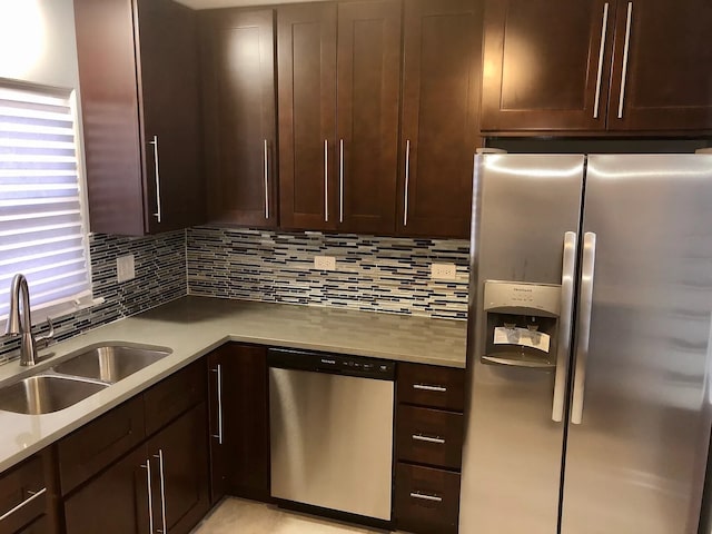 kitchen featuring light countertops, backsplash, appliances with stainless steel finishes, a sink, and dark brown cabinetry