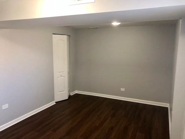 unfurnished room featuring dark wood-style floors, visible vents, and baseboards