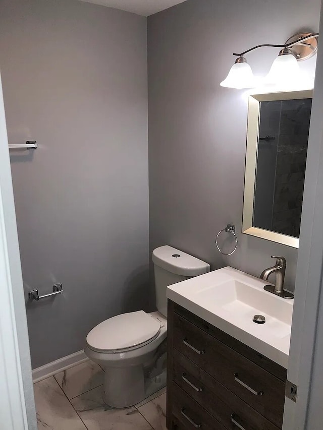 bathroom featuring marble finish floor, baseboards, vanity, and toilet