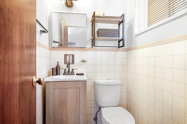 bathroom with toilet, tile walls, and vanity