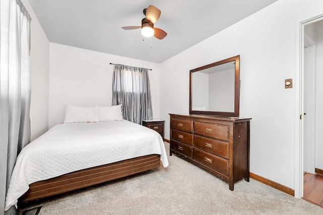 bedroom featuring light colored carpet, a ceiling fan, and baseboards