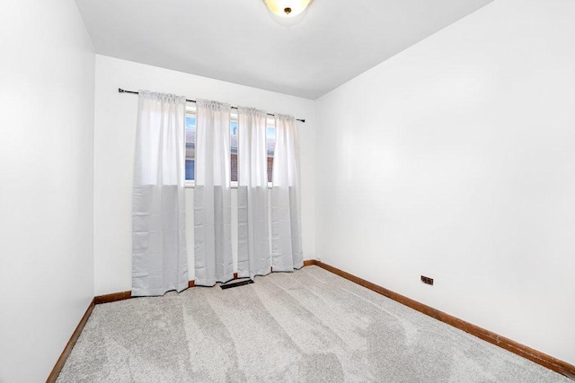 carpeted empty room featuring baseboards