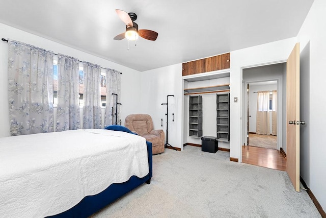 bedroom with a closet, multiple windows, light colored carpet, and a ceiling fan