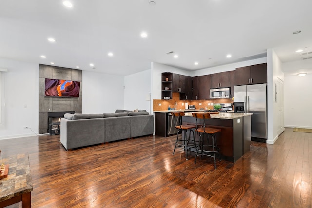 kitchen featuring a fireplace, a kitchen island, appliances with stainless steel finishes, decorative backsplash, and open shelves